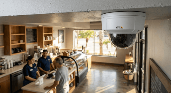 Modern security camera in foreground with business interior visible in background